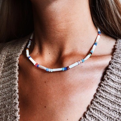 Colar colorido de contas usadas no pescoço de mulher com suéter bege