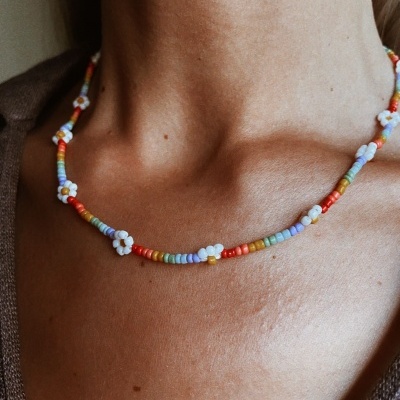 Colar curto colorido de contas e flores brancas no pescoço