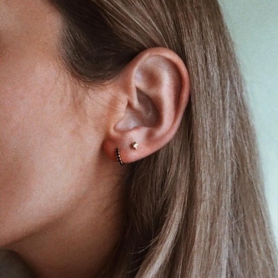 Brincos pequenos em orelha feminina com cabelo castanho claro