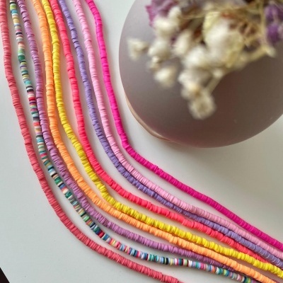 Colares coloridos feitos de discos pequenos com vaso e flores secas ao fundo