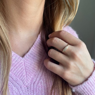 Anel de prata texturizado numa mão feminina com suéter rosa claro