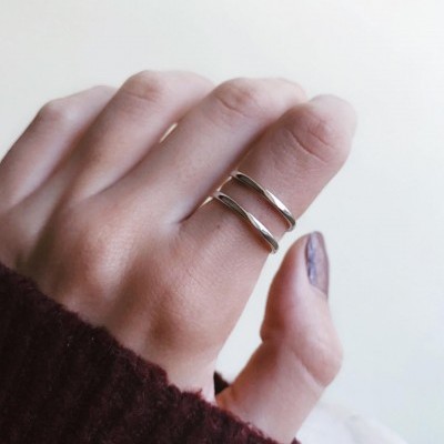 Anel em metal prateado com dois segmentos no dedo indicador