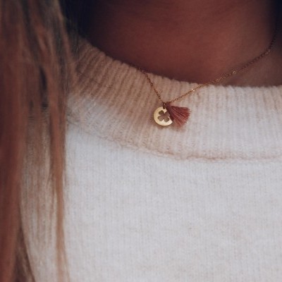 colar delicado com pendente dourado e franjas castanhas, usado com camisola branca