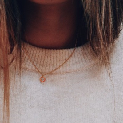 Colar dourado com pendente circular em camisola bege