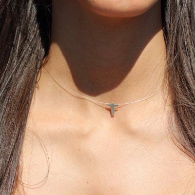 Colar com pendente pequeno em metal prateado no pescoço de mulher