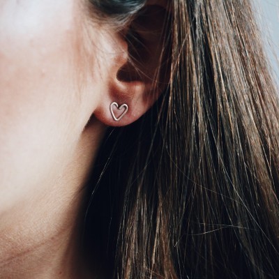 Brinco prateado em forma de coração na orelha de mulher