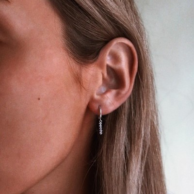 Brinco prateado pendente na orelha de mulher loira