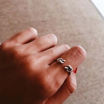 Mão com anel em prata com design de nós