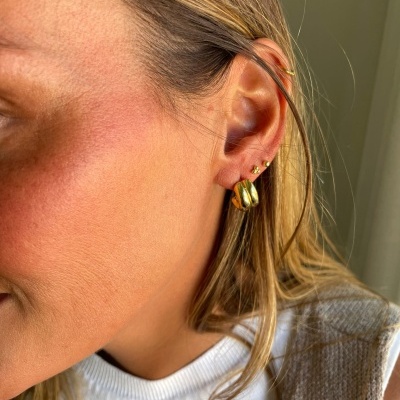 Orelha feminina com brincos dourados e cabelo loiro