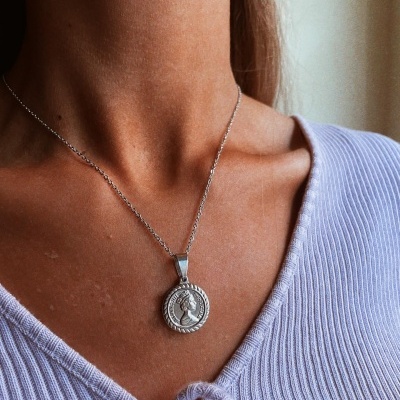 Colar prateado com pendente religioso em camisola lilás canelada