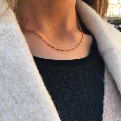 Colar fino com contas vermelhas e corrente dourada no pescoço