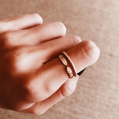 anel dourado aberto com textura e detalhes no dedo