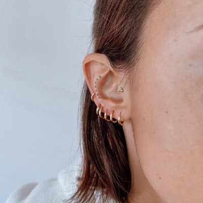 Orelha com seis brincos dourados de argola e um brinco helix dourado