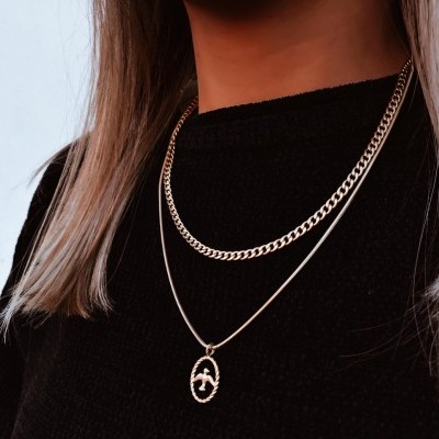 Colares dourados em duas camadas usados por pessoa com roupa preta