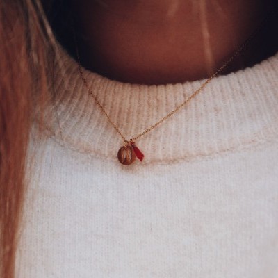 Colar delicado em corrente dourada com pendentes âmbar e vermelho, usado com camisola branca