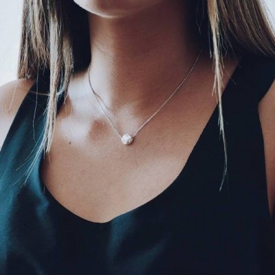 Colar prateado com pendente de pérola usado com blusa preta