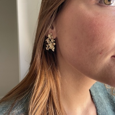Brinco dourado floral em orelha feminina