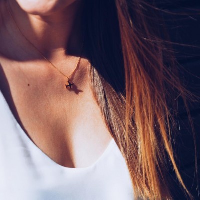 Colar dourado com pendente em forma de avião