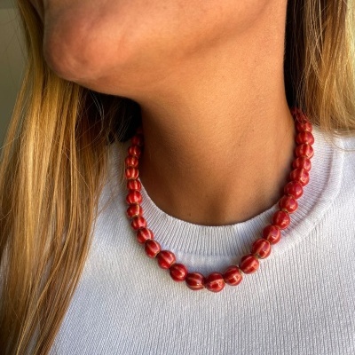 Colar de contas vermelhas com padrão branco usado ao pescoço