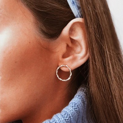 Brinco de argola torcida prata na orelha de mulher com camisola azul