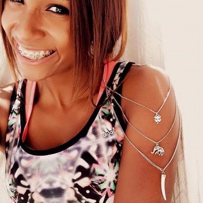 Mulher a sorrir com top desportivo Adidas e pulseiras prateadas com pendentes no braço