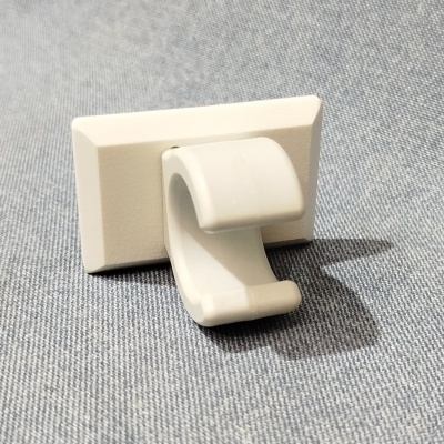 Gancho branco de plástico colocado sobre tecido cinza