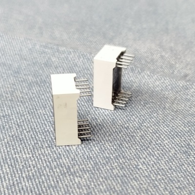 Componentes eletrónicos brancos com pinos metálicos sobre tecido cinza tipo ganga