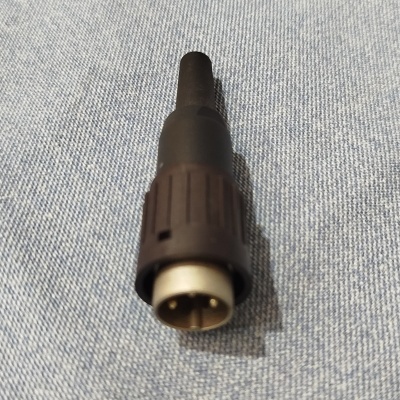 Cabo adaptador preto e metálico com dois pinos, sobre tecido azul claro