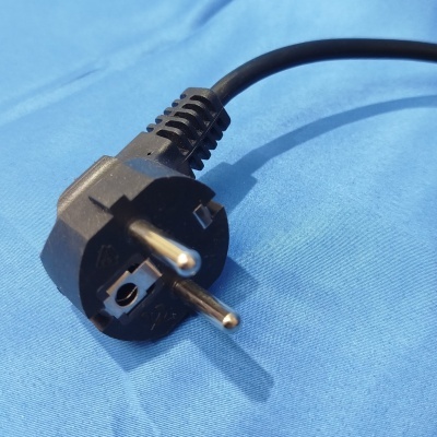 Ficha elétrica preta de três pinos sobre superfície azul