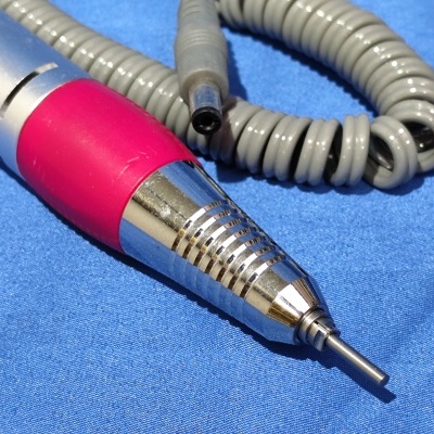 Ferramenta elétrica portátil prateada e vermelha com cabo cinzento sobre fundo azul