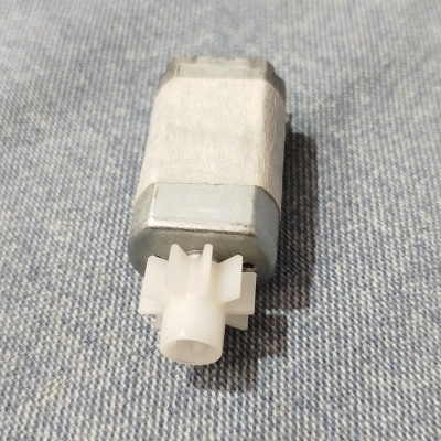 Motor elétrico pequeno com engrenagem de plástico branca sobre tecido azul