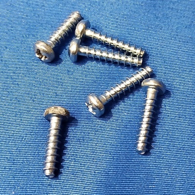 Seis parafusos pequenos em metal prateado sobre superfície azul texturizada