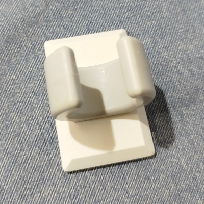 Prendedor plástico branco com dois encaixes sobre tecido azul claro