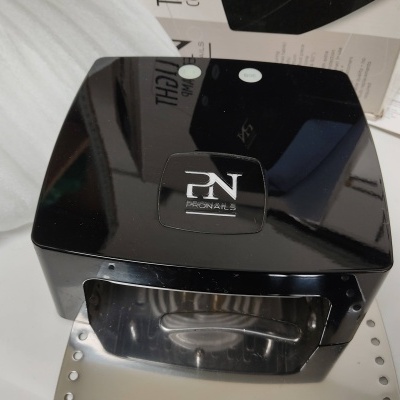 Dispositivo preto brilhante Ironnail S sobre superfície branca com documentos ao redor