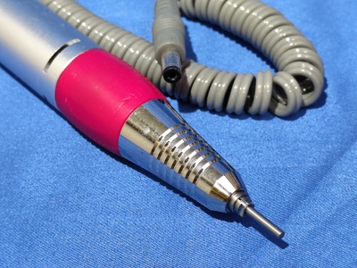 Ferramenta elétrica portátil prateada e vermelha com cabo cinzento sobre fundo azul