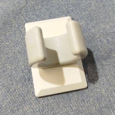 Prendedor plástico branco com dois encaixes sobre tecido azul claro