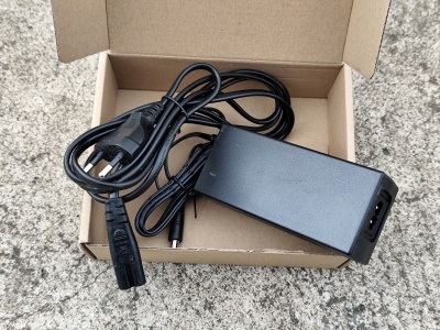 Adaptador de alimentação preto com cabo elétrico e ficha europeia na caixa de cartão