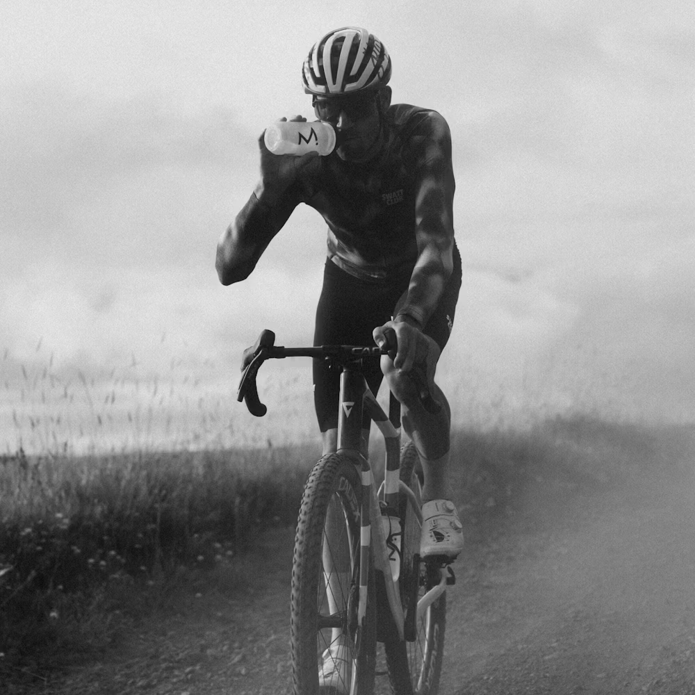 Ciclista a beber água numa bicicleta em estrada de terra