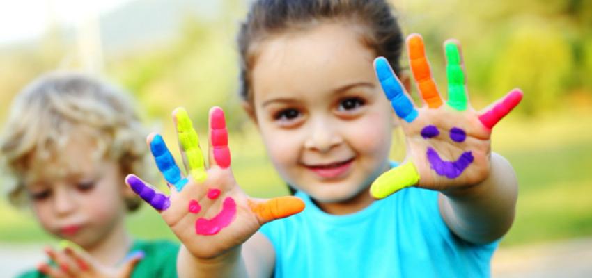 VITAMINAS E MINERAIS NAS CRIANÇAS Crianças com mãos pintadas em várias cores e sorrisos desenhados nas palmas