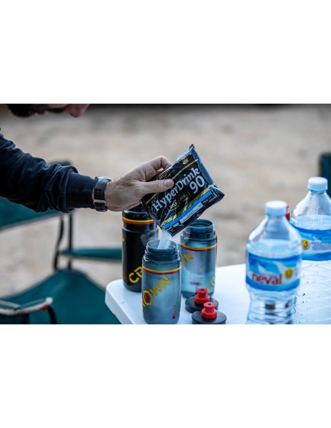 Pessoa a verter saqueta HyperDrink 90 em bidão prateado ao ar livre