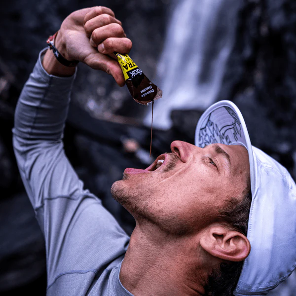 Homem a consumir líquido de embalagem pequena com texto 'VOLTAR MAIS FORTE' ao ar livre