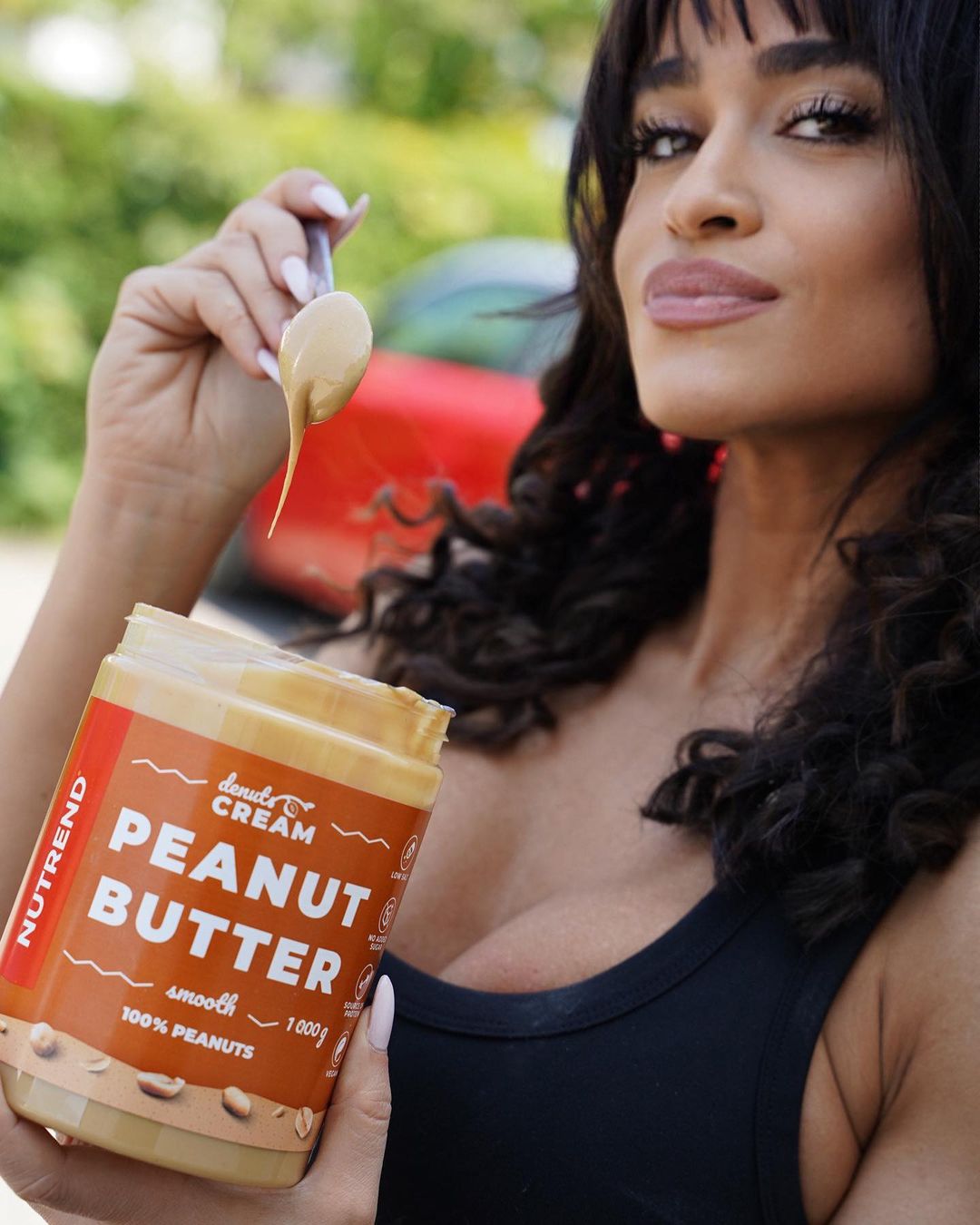 Frasco de manteiga de amendoim com mulher segurando colher e frasco em ambiente exterior