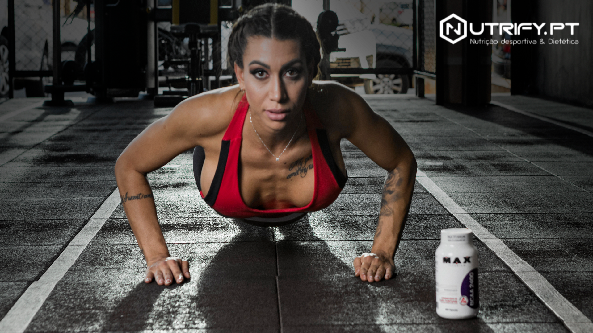 Mulher a fazer flexões em ginásio com suplemento alimentar ao lado