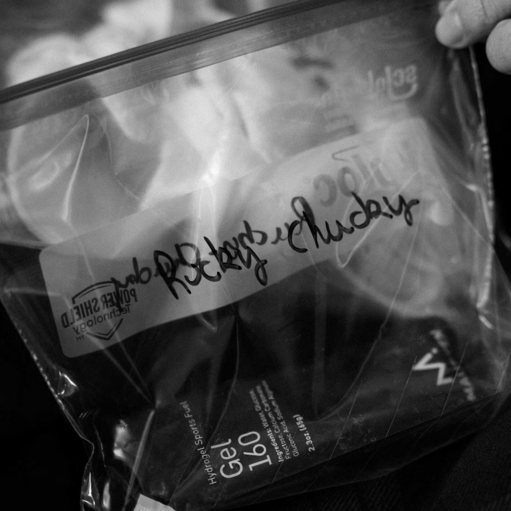 Saco plástico transparente com embalagem de gel desportivo preta com texto manuscrito.