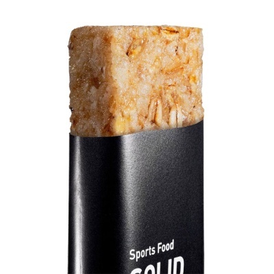 Barra alimentar sólida metade visível em embalagem preta com texto branco