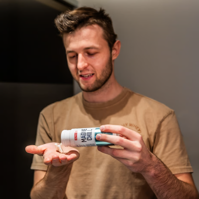 Homem a verter cápsulas de suplemento magié chill na mão