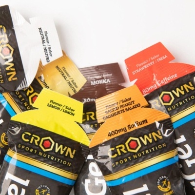 Pacotes coloridos de suplementos Crown Sport Nutrition com texto de sabores e conteúdos sobre fundo branco