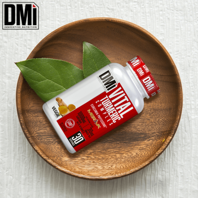 Frasco do suplemento Vital Turmeric Complex em tigela de madeira com folhas verdes