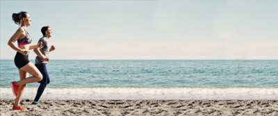 Duas pessoas a correr na praia com roupa desportiva