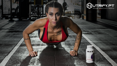 Mulher a fazer flexões em ginásio com suplemento alimentar ao lado